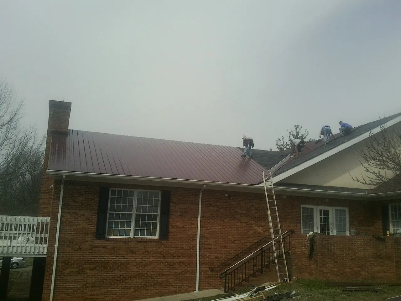 Crew setting red metal roofing panels on a brick home in Bladensburg