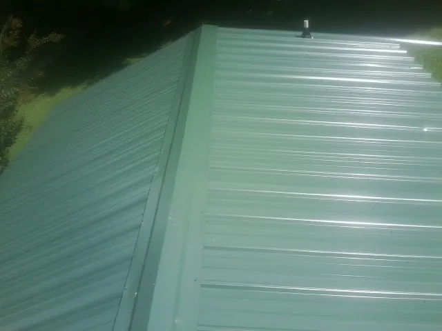 New green metal panels meeting at the ridge of a roof — Flat Roof Repair work by our crew in Bladensburg